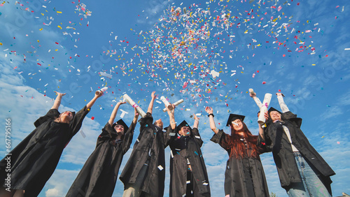 Konstfotografi Happy graduates throwing up colorful confetti against the blue summer sky