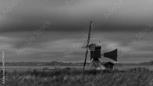 Old wooden windmill in the Dutch meadows under dark, ominous clouds