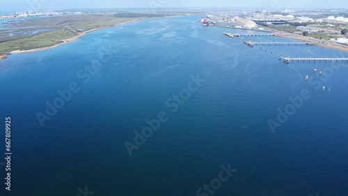 Flying over the Odiel river through the outer port of Huelva industrial zone for loading and unloading ships