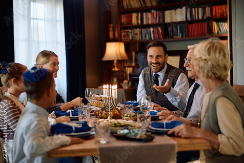 Happy Jewish multigeneration talks while having lunch at dining table on Hanukkah.