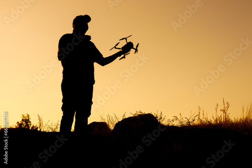 silhouette of a man holding a quadcopter in his hand outside the room