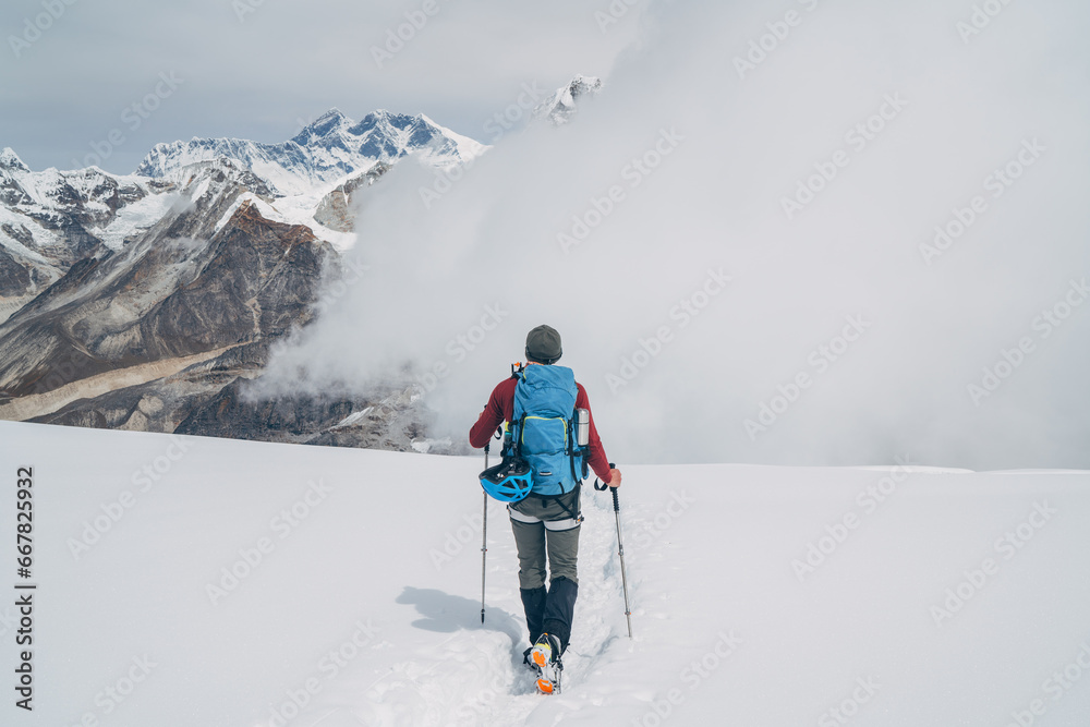 Climber with backpack and trekking poles descending Mera peak high slopes at cca 6000m enjoying legendary Mount Everest, Nuptse, Lhotse with South Face wall, Makalu beautiful High Himalayas.