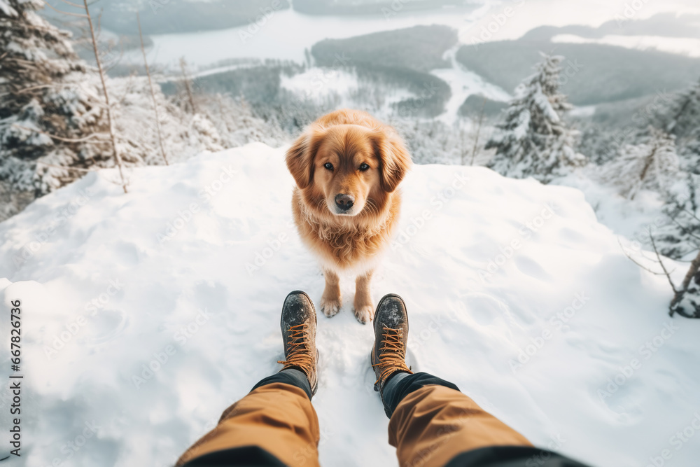 Cute ginger dog standing by owner legs on snowy winter mountains landscape Cute ginger dog standing by owner legs on snowy winter mountains landscape