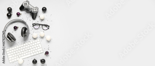 Computer keyboard with headphones, game pad, eyeglasses and Christmas decor on white background with space for text