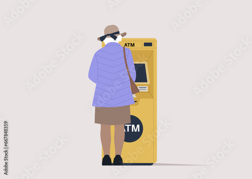 A rear view of a senior lady withdrawing money from an outdoor ATM machine