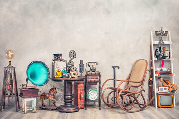 Antique gramophone, rocking chair, vintage movie projector, tape recorder, mic, film camera, mask, telephone, clock, books, fiddle, old typewriter, radio, TV, candlestick. Retro style filtered photo