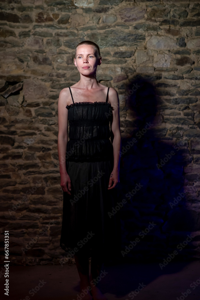 Capturing the essence of a middle-aged woman, approximately 40, donning a black dress and a stylish short hairstyle, illuminated by intense light against a brick wall background Capturing the essence of a middle-aged woman, approximately 40, donning a black dress and a stylish short hairstyle, illuminated by intense light against a brick wall background