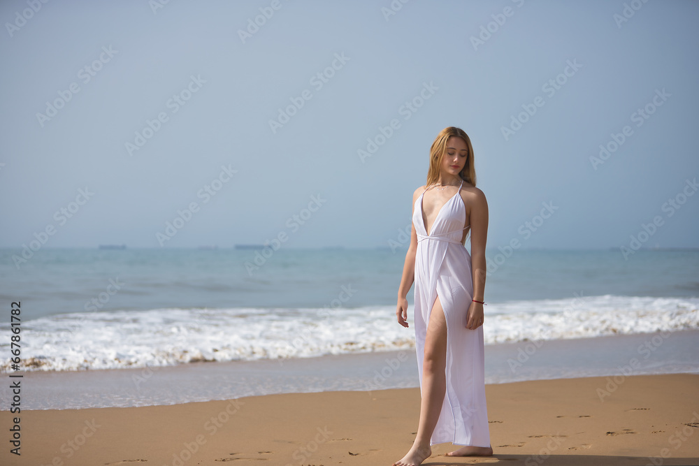 Young, beautiful, blonde woman in a white dress, walking on a lonely beach, relaxed and calm. Concept peace, tranquility, solitude, finding oneself. Young, beautiful, blonde woman in a white dress, walking on a lonely beach, relaxed and calm. Concept peace, tranquility, solitude, finding oneself.