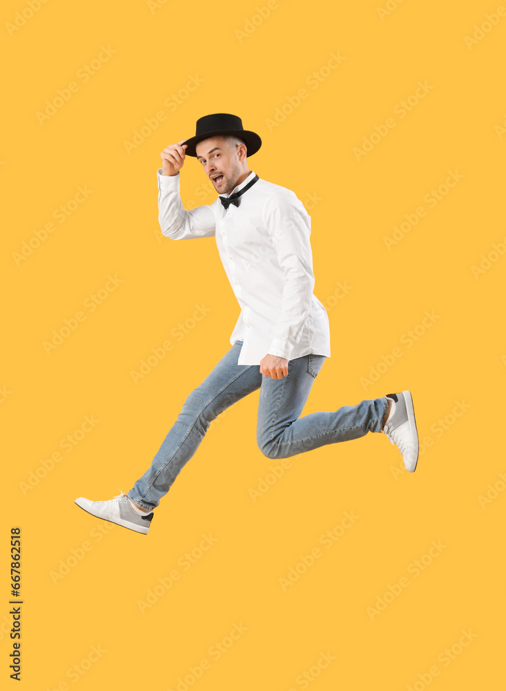 Happy young man jumping on yellow background
