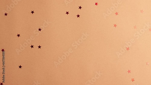 Human hands in white sweater take a white paper gift with a red satin ribbon bow on brown background with red stars shapes. Stop motion animation Christmas Holidays concept flat lay