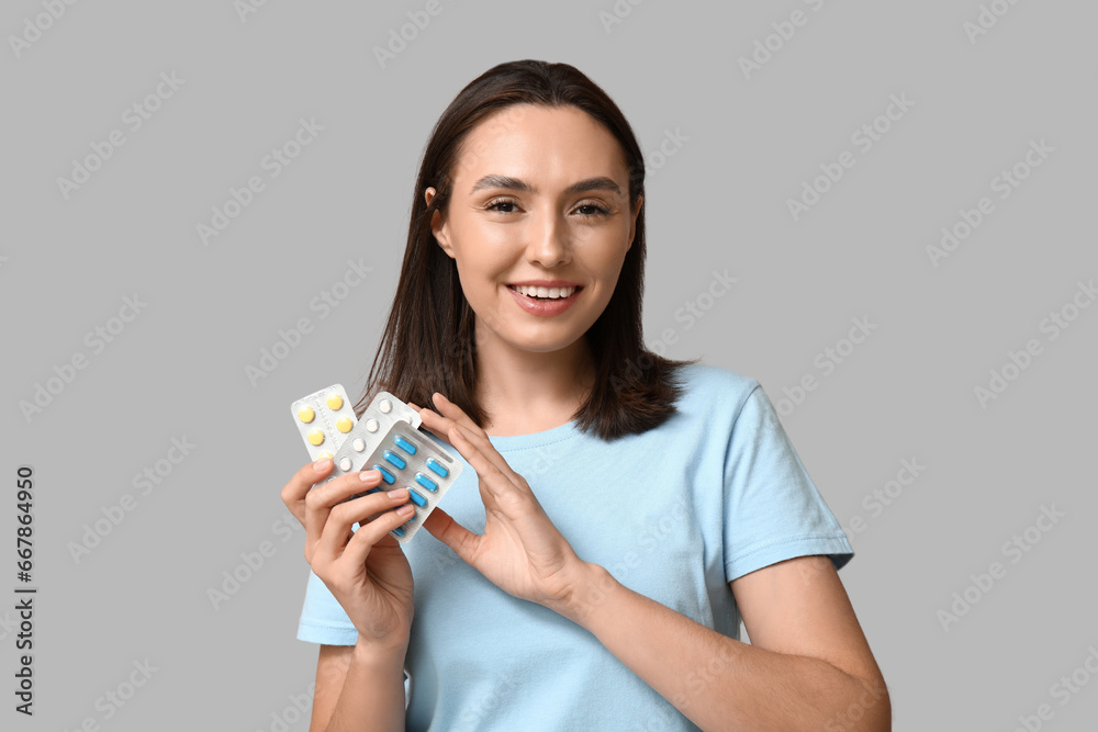Pretty young woman with pills on grey background Pretty young woman with pills on grey background