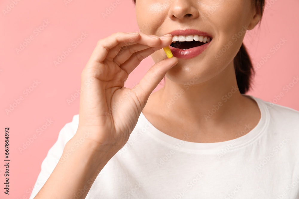 Woman taking pill on pink background, closeup Woman taking pill on pink background, closeup
