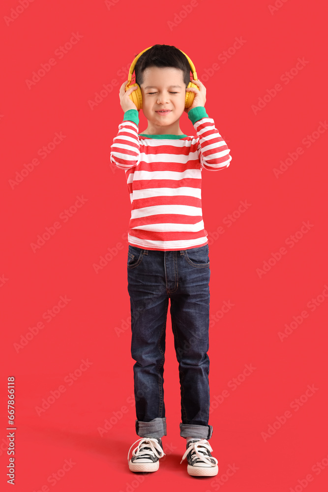 Cute little Asian boy in headphones on red background Cute little Asian boy in headphones on red background