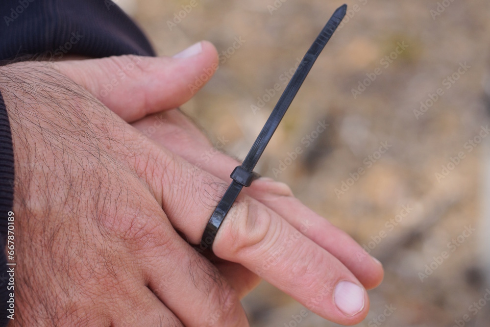 a black plastic tie ties two fingers on a mans hands on the street