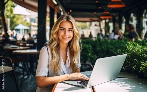 A smiling woman sitting with a laptop on a sunny restaurant terrace