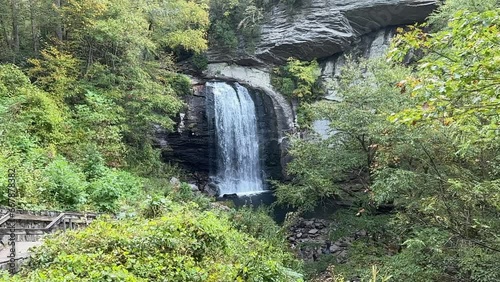 Beautiful wide waterfall with white water cascading in slow motion over darkened rocks in the mountains