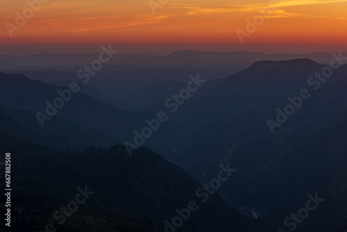 sun setting behind the mountains in Yosemite National Park in California as viewed in Glacier Point road .