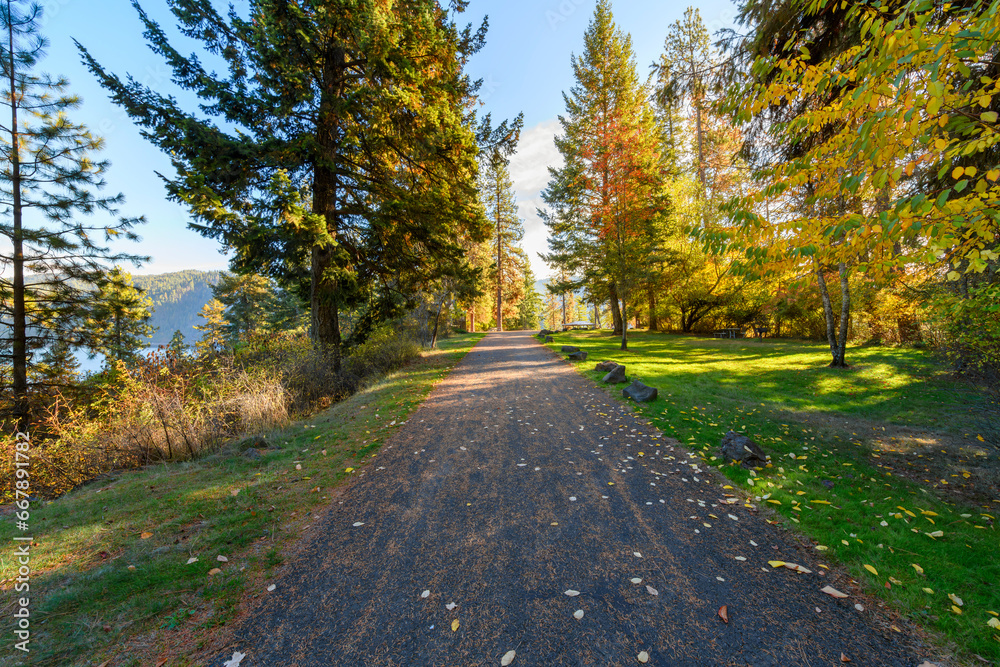 Paved path along the lakefront walking centennial trail at the Coeur d'Alene Parkway State Park at Higgens Point on the lake at autumn, in Coeur d'Alene, Idaho USA. Paved path along the lakefront walking centennial trail at the Coeur d'Alene Parkway State Park at Higgens Point on the lake at autumn, in Coeur d'Alene, Idaho USA.