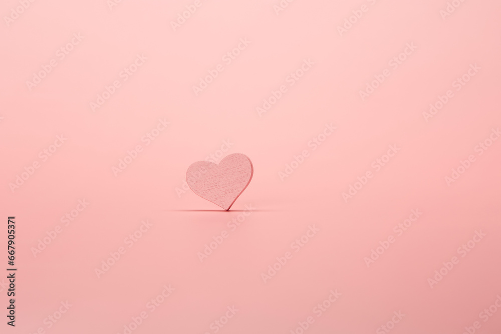 Pink color wooden heart isolated on the bright solid pink fond background