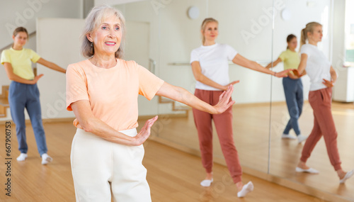 Aged lady learning to dance in studio during group lesson.