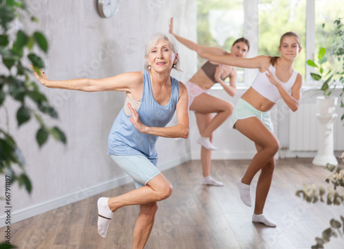 Three generations of women are learning sports Latin American dances in studio class. Joint pastime, active hobby