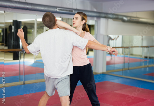 European woman learning elbow strike move during self-defense training.