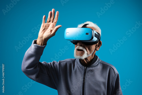 ELDERLY MAN WEARING A VIRTUAL REALITY HELMET INTERACTING WITH IMMERSIVE CONTENT ON PLAIN LIGHT BLUE BACKGROUND. COPY SPACE. CONCEPT: CHRISTMAS GIFT, TECHNOLOGY AND ADULTS, MODERN GRANDPARENTS.