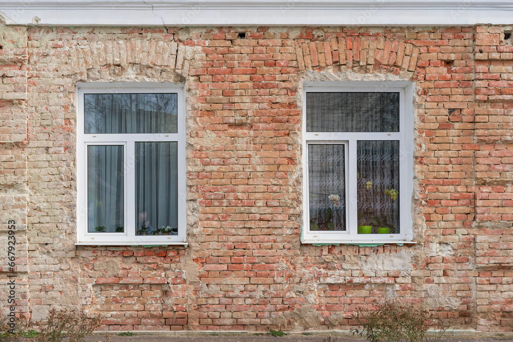 White three-section PVC windows. Brick old wall without plaster.