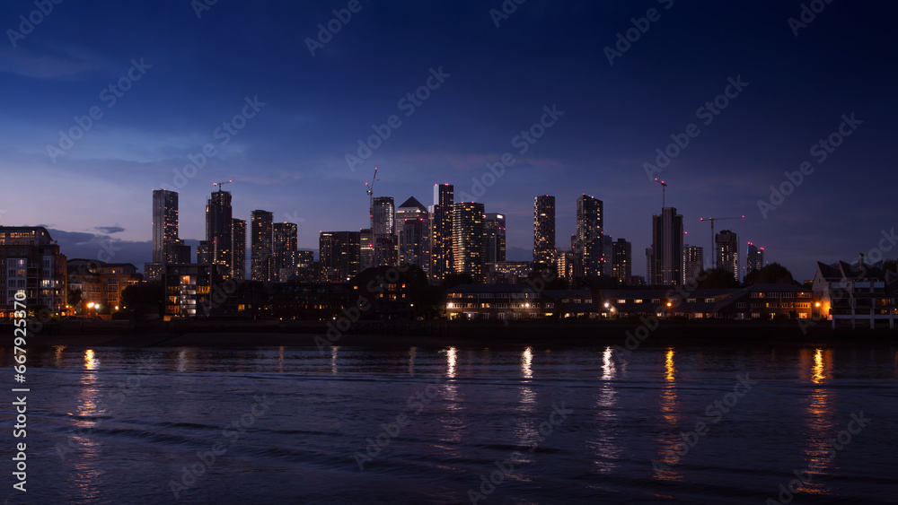 Fototapeta premium Night view on Isle of Dogs and Canary Wharf from the bank of the Thames river, Grivich district. 16x9 photo