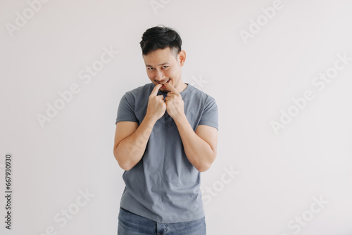 Shy and embarrassment funny asian man in blue t-shirt isolated on white wall.