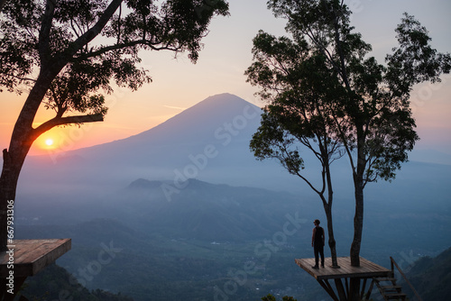 Silhouette of a man standing on the Lahangan Sweet viewpoint, overlooking Mount Agung, Bali island. photo