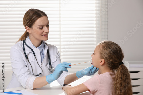 Doctor taking throat swab sample from girl`s oral cavity indoors