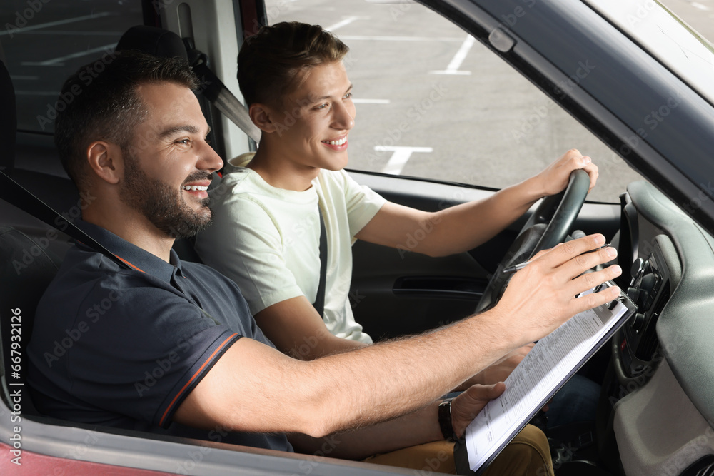 Driving school. Happy student passing driving test with examiner in car at parking lot Driving school. Happy student passing driving test with examiner in car at parking lot