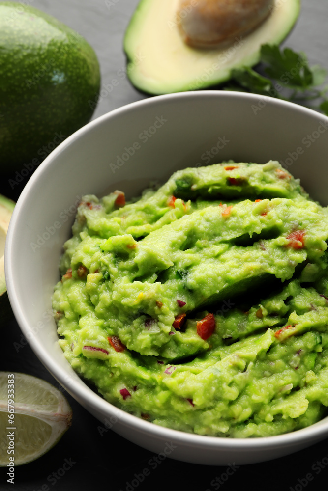 Delicious guacamole, fresh avocado and parsley on grey table Delicious guacamole, fresh avocado and parsley on grey table