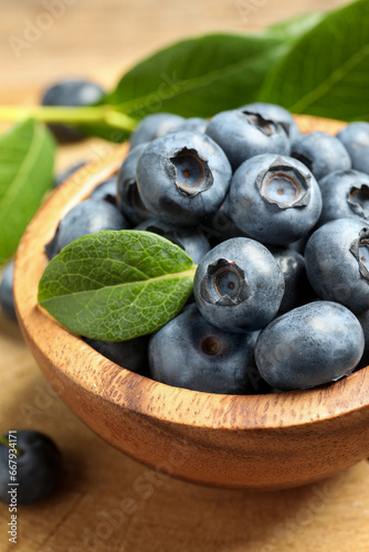 Bowl of tasty fresh blueberries on wooden table  closeup