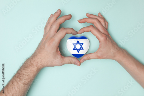 Heart with print of Israel flag in female and male hands.. Flat lay. Copy space.