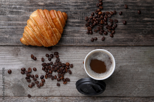 Coffee to go. Paper cup with tasty drink, croissant and beans on wooden table, flat lay