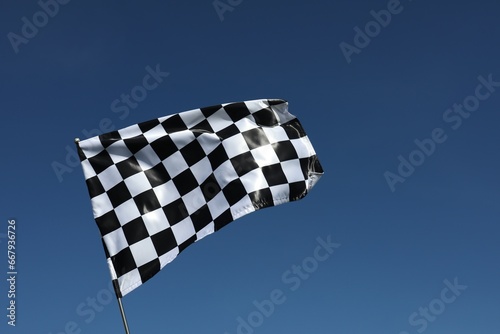 One checkered flag against blue sky outdoors, low angle view and space for text