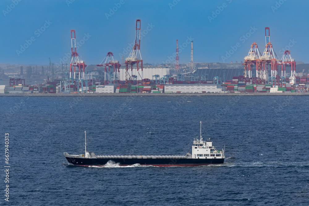 東京湾を航行する貨物船とガントリークレーン