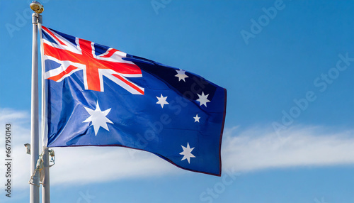 Close up view of an AUSTRALIAN flag waving on a flagpole, with blue sky background and copy space