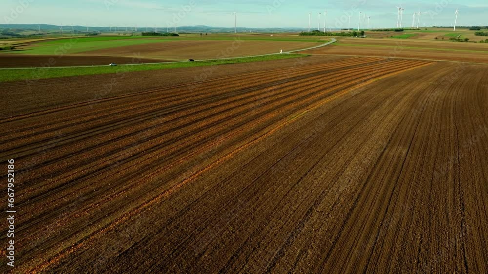 Scenic Aerial View Of A Land During Harvest Season Near Road Overlooking Wind Turbines. Scenic Aerial View Of A Land During Harvest Season Near Road Overlooking Wind Turbines.