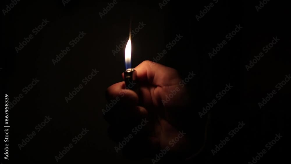 male hand flickering a lighter in a dark room male hand flickering a lighter in a dark room