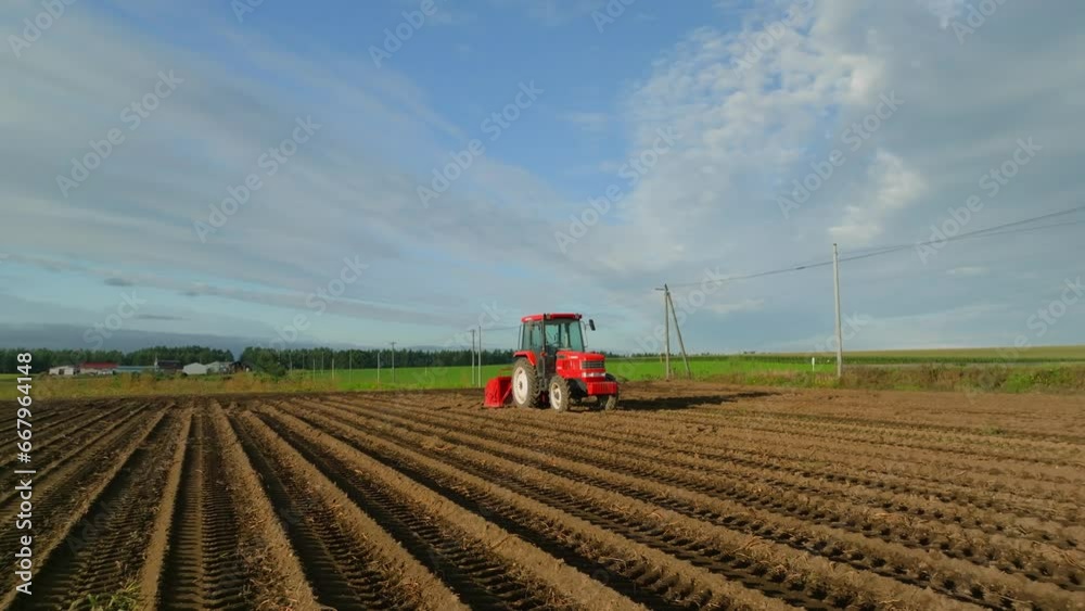 Slow rotation around bright red tractor in plowed field in morning light Slow rotation around bright red tractor in plowed field in morning light