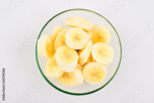 Top view of chopped banana in bowl on white background