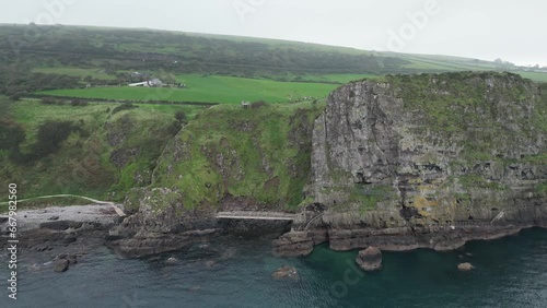 Aerial dolly backwards shot of majestic cliffs by the sea from the Gobbins Cliffs while traveling through the gorgeous Northern Ireland on a calm morning photo