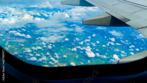 Aerial view of the blue sky and clouds through an airplane window, vibrant natural scenery. Travel concept, traveler, trip, vacation, tourism, landscape, background