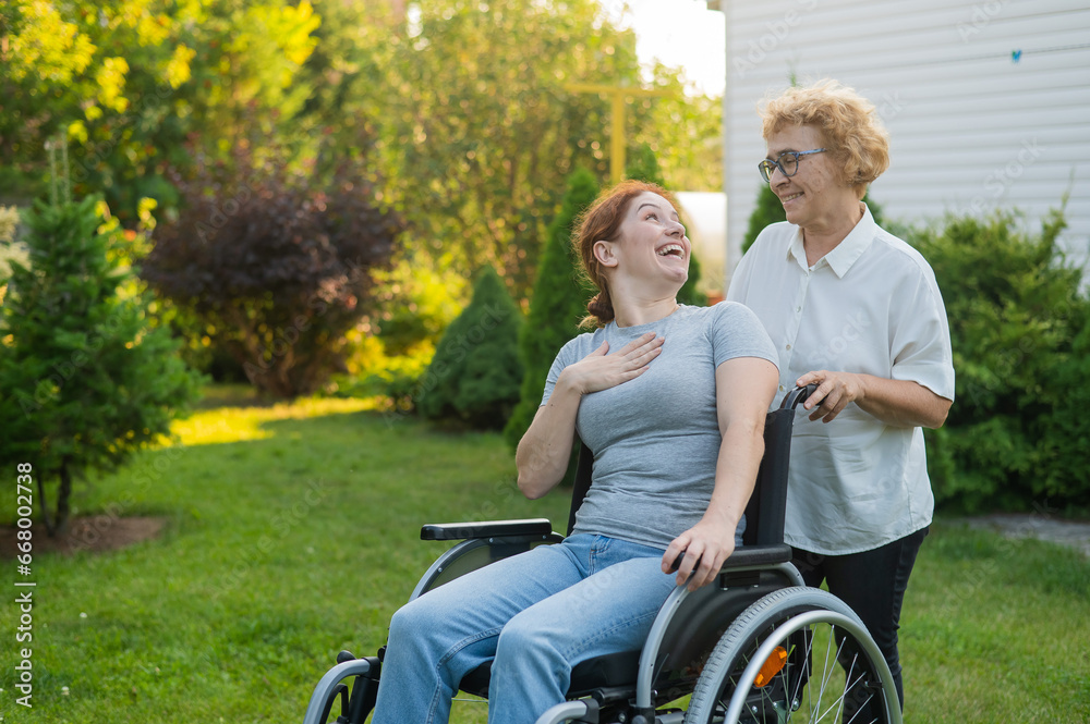 An elderly woman is carrying an adult daughter sitting in a wheelchair. Walk outdoors. An elderly woman is carrying an adult daughter sitting in a wheelchair. Walk outdoors.