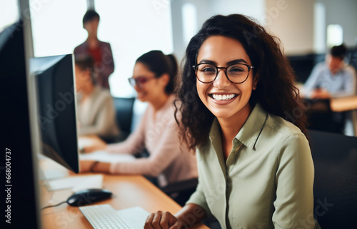 Portrait of young woman working on laptop computer in modern office, Confident employee smiling happily while working with coworkers.