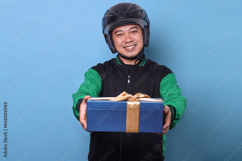 Cheerful online taxi driver wearing helmet giving a gift package to customer