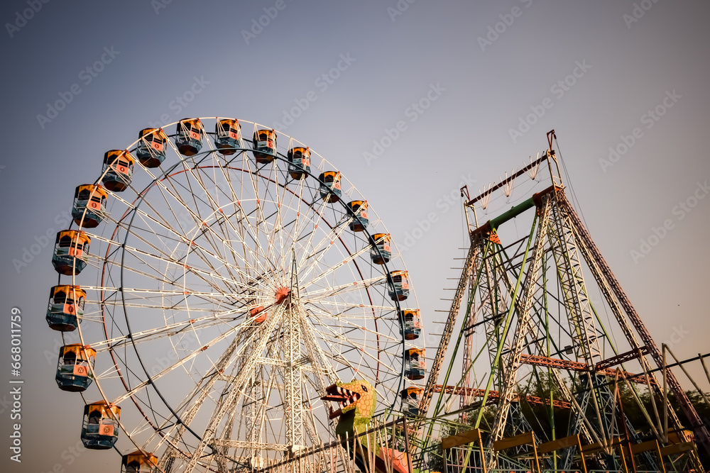 Closeup of multi-coloured Giant Wheel during Dussehra Mela in Delhi, India. Bottom view of Giant Wheel swing. Ferriswheel with colourful cabins during day time. Closeup of multi-coloured Giant Wheel during Dussehra Mela in Delhi, India. Bottom view of Giant Wheel swing. Ferriswheel with colourful cabins during day time.